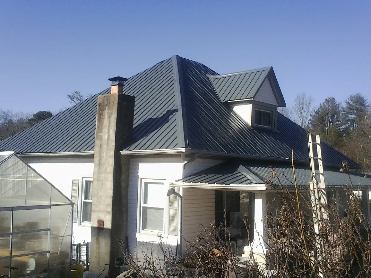 Dark blue standing seam metal roof on a white farmhouse with dormer — Slate & Tile Roof Repair by Roofing Brothers in Sonoma